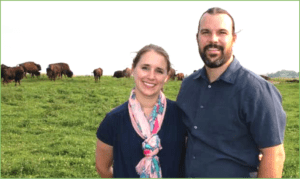 Young couple with large livestock in the distance.