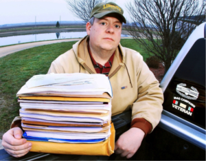 Man standing with stack of papers beside pickup truck
